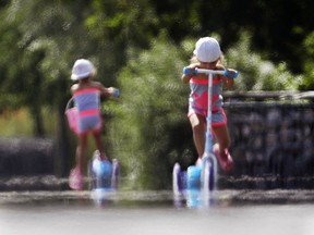 Two little girls ride their scooters through the shimmering heat on the tarmac of a former military airport in Frankfurt, Germany, on a hot Monday, July 30, 2018.
