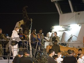 Migrants desembark from Frontex ship "Protector" at the port of Pozzallo, Sicily, Italy, in the early hours of Monday, July 16, 2018. Migrants aboard two border patrol ships have disembarked in a Sicilian port after a half-dozen European countries promised to take some of them in rather than have Italy process their asylum claims alone.