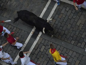 Revellers run next to a fighting bull from the Cebada Gago ranch during the third day of the running of the bulls at the San Fermin Festival in Pamplona, northern Spain, Monday, July 9, 2018. Revellers from around the world flock to Pamplona every year to take part in the eight days of the running of the bulls.