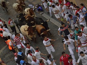 Revellers run next to fighting bulls from the Miura ranch during the last day of the running of the bulls at the San Fermin Festival in Pamplona, northern Spain, Saturday, July 14, 2018. Revellers from around the world flock to Pamplona every year to take part in the eight days of the running of the bulls.