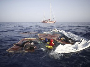 Rescue workers from the Proactiva Open Arms Spanish NGO retrieve the bodies of an adult and a child amid the drifting remains of a destroyed migrant boat off the Libyan coast, on Tuesday July 17, 2018. A migrant rescue aid group accused Libya's coast guard of abandoning three people in the Mediterranean Sea, including an adult woman and a toddler who died, after intercepting some 160 Europe-bound migrants on Monday near the shores of the northern African country. (Proactiva Open Arms via AP)