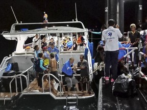 Rescued tourists from a boat that sank are helped onto a pier Thursday, July 5, 2018, on the island of Phuket, southern Thailand.