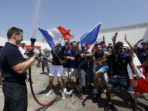 A firefighter sprays water to cool off French supporters at a fan zone in Marseille, southern France, prior to the final match between France and Croatia at the 2018 soccer World Cup in the Luzhniki stadium in Moscow, Sunday, July 15, 2018.