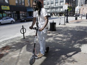 In this Tuesday, July 24, 2018 photo, Vatic Kuumba, of Providence, R.I. rides a BIRD electric scooter in downtown Providence. The rental vehicles began appearing in several New England cities last week without warning. Cambridge, Mass., sent a letter to Los Angeles-based startup Bird Rides Inc., warning that it's illegal to operate its business in the city without prior authorization. Providence is crafting a new policy.