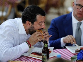 FILE - In this Thursday, July, 5, 2018 photo, Italian Interior Minister Matteo Salvini eats a hamburger at Villa Taverna, the residence of the US Ambassador to Italy, on the occasion of the July 4 Independence Day celebrations, in Rome, Thursday, July 5, 2018. Five weeks after taking national office opinion polls indicate that Salvini's anti-migrant, anti-European Union party has soared in popularity.