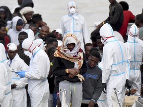 FILE - In this Wednesday, June 13, 2018 file photo, migrants wait to disembark from Italian Coast Guard vessell "Diciotti" as it docks at the Sicilian port of Catania, southern Italy. As NATO allies convene, one issue not on their formal agenda but never far from their thoughts is immigration, even though illegal border crossings are decreasing on both sides of the Atlantic. The separation of families at the U.S.-Mexico border and Italy's refusal to let shipwrecked migrants disembark in its ports illustrate the hardening positions on border control in Washington and European capitals.