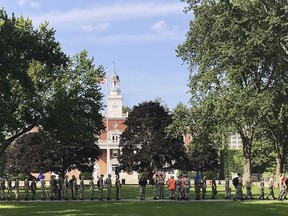 CORRECTS IDENTIFICATION OF SUBJECTS IN PHOTO, REMOVES REFERENCE OF STUDENTS: In this Monday, July 16, 2018 photo, a group in military fatigues walks IN front of Jackman Hall, rear, on the campus of Norwich University in Northfield, Vt. Norwich has become the latest school to offer income share agreements, where colleges receive a percentage of the student's future salary, in place of some student loans.