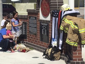 A woman who would only identify herself as a niece of shooting victim Charles 'Bert' Miller, is joined by her children as she places flowers at a makeshift memorial Monday, July 23, 2018, in Fallon, Nev., outside the fire department where Miller was a longtime volunteer firefighter. Police in the northern Nevada city are trying to determine why a 48-year-old man walked into his Mormon church on Sunday, July 22, 2018, and opened fire, killing Miller and injuring another person.