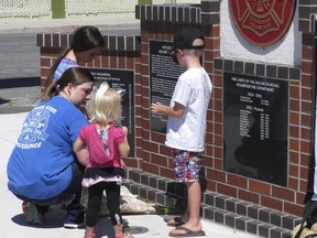 A woman who would only identify herself as a niece of shooting victim Charles "Bert" Miller, is joined by her children as she places flowers at a makeshift memorial Monday, July 23, 2018, in Fallon, Nev., outside the fire department where Miller was a longtime volunteer firefighter.