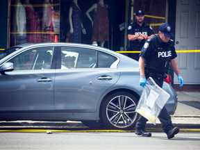 Police investigate a car with a bullet hole within the scene of a mass shooting on Danforth Avenue in east Toronto, July 23, 2018.