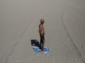 Luciano Paesani, 53, stands on a towel not to burn his feet on the beach Friday, July 6, 2018, in Long Beach, Calif. Record-breaking heat hit the state from the desert to the sea.