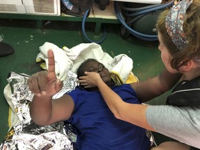 A rescue worker from the Proactiva Open Arms Spanish NGO helps a migrant, rescued off the Libyan coast, on Tuesday July 17, 2018.