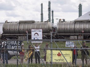 Protesters stand outside the fence as Prime Minister Justin Trudeau visits Kinder Morgan in Edmonton Alta, on Tuesday June 5, 2018.