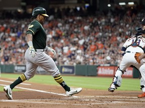 Oakland Athletics' Khris Davis, left, scores as Houston Astros starting pitcher Lance McCullers Jr., right, covers home plate during the first inning of a baseball game Wednesday, July 11, 2018, in Houston.