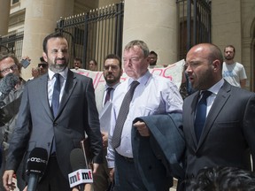Claus-Peter Reisch, the German captain of Lifeline, a private ship that rescues migrants, is flanked by his lawyers as he leaves after an arraignment hearing in Valletta, Malta's capital, Monday, July 2, 2018. The Lifeline rescued 234 migrants in waters off Libya, then headed to Malta after Italy refused entrance to the ship. Reisch was charged with using the boat in Maltese waters without proper registration or license.