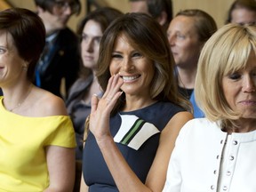 U.S. first lady Melania Trump, center, waves as she prepares to listen to a concert at the Queen Elisabeth Music Chapel in Waterloo, Belgium, during a spouses program on the sidelines of the NATO summit on Wednesday, July 11, 2018. At right is Brigitte Macron, the wife of French President Emmanuel Macron and at left is Amelie Derbaudrenghien, the partner of Belgian Prime Minister Charles Michel.
