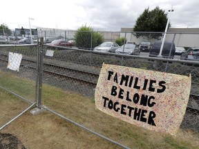 A sign that reads "Families belong Together" hangs on a fence outside the Northwest Detention Center in Tacoma, Wash., Tuesday, July 10, 2018. The Trump administration rushed to meet a deadline Tuesday for reuniting dozens of youngsters forcibly separated from their families at the U.S.-Mexico border.