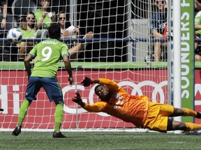 New York City goalkeeper Sean Johnson, right, can't stop a goal kicked by Seattle Sounders midfielder Cristian Roldan as Sounders' Raul Ruidiaz (9) looks on during the first half of an MLS soccer match, Sunday, July 29, 2018, in Seattle.