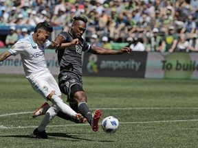 Seattle Sounders forward Raul Ruidiaz, left, kicks the ball past Vancouver Whitecaps defender Kendall Waston, right, during the second half of an MLS soccer match Saturday, July 21, 2018, in Seattle. The Sounders won 2-0.