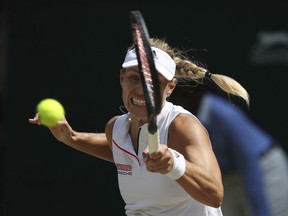 Angelique Kerber of Germany returns a ball to Jelena Ostapenko of Latvia during their women's semifinal match at the Wimbledon Tennis Championships in London, Thursday July 12, 2018.