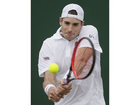 John Isner of the US plays a return to Ruben Bemelmans of Belgium during their men's singles match on the third day at the Wimbledon Tennis Championships in London, Wednesday July 4, 2018.