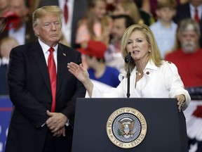 FILE - In this May 29, 2018 file photo, President Donald Trump listens as Rep. Marsha Blackburn, R-Tenn., speaks at a rally at the Nashville Municipal Auditorium in Nashville, Tenn. Blackburn is supposed to do well among Tennessee's hog farmers and whiskey makers.  Yet the Republican Senate candidate is struggling to explain President Donald Trump's nascent trade war to her state's local business community.