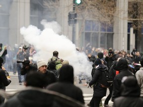 FILE - In this Jan. 20, 2017, file photo, police deploy smoke and pepper grenades during clashes with protesters in northwest Washington. The U.S. government is dropping charges against the last 39 people accused of taking part in a violent protest on the day of President Donald Trump's inauguration.