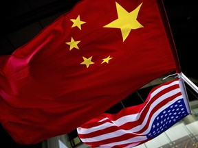 FILE - In this Nov. 7, 2012, filephoto, U.S. and Chinese national flags are hung outside a hotel during the U.S. Presidential election event, organized by the U.S. embassy in Beijing. A government report is outlining how spy services from China, Russia and Iran are hard at work trying to steal trade secrets and proprietary information from U.S. companies, government labs and universities.