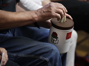 A patron puts a bill in a donation bucket, which features a red rose symbol, during a meeting of members of the Southern Maine Democratic Socialists of America in Portland, Maine, Monday, July 16, 2018. On the ground in dozens of states, there is new evidence that democratic socialism is taking hold as a significant force in Democratic politics. The red rose is a symbol of democratic socialism.