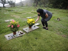 In this  July 1, 2018 photo, Ivonne de Gutierrez visits the Cemetery of the East where her son, nephew and aunts are buried in Caracas, Venezuela. Gutierrez says the headstones marking the graves of her nephew and two aunts have disappeared, and that so far looters have skipped over her son's headstone.