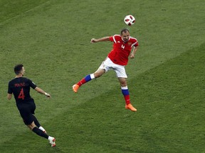 Russia's Sergei Ignashevich heads the ball away from Croatia's Ivan Perisic, left, during the quarterfinal match between Russia and Croatia at the 2018 soccer World Cup at the Fisht Stadium in Sochi, Russia, Saturday, July 7, 2018.