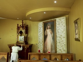 In this Sunday, July 22, 2018 photo. Rev. Erick Alvarado kneels in the chapel altar inside the Jesus of Divine Mercy church, in Managua, Nicaragua. Alvarado said police have yet to come to investigate the July 13-14 overnight attack on the church that is still pocked from hundreds of bullet impacts.