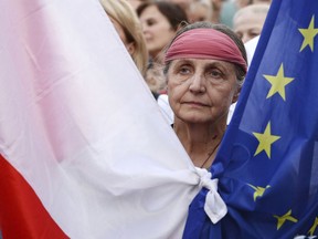 A protester hold Polish and European Union flags tied together as people rally in front of the Supreme Court, in Warsaw, Poland, Wednesday, July 4, 2018. Poland's international isolation and political uncertainty at home has deepened as a purge of the Supreme Court's justices took effect, with the chief justice defiantly refusing to step down.