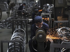 In this June 4, 2018, photo, a worker wields steel wheel rims at a factory in Hangzhou in east China's Zhejiang province. China launched a trade investigation Monday, July 23, 2018 of steel from Europe and South Korea, potentially complicating efforts to recruit them as allies in its tariff dispute with U.S. President Donald Trump. (Chinatopix via AP)