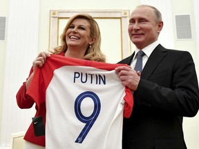 Croatian President Kolinda Grabar Kitarovic, left, presents a T-shirt to Russian President Vladimir Putin during their meeting in the Kremlin in Moscow, Russia, Sunday, July 15, 2018.