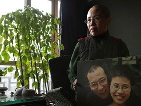 FILE - In this Dec. 6, 2012, file photo, Liu Xia, wife of 2010 Nobel Peace Prize winner Liu Xiaobo, poses with a photo of her and her husband during her first interview in more than two years at her home in Beijing, China. A person briefed on the matter said Tuesday, July 10, 2018, that Liu Xia, the widow of Chinese Nobel Peace Prize Laureate Liu Xiaobo, has left China for Europe after eight years under house arrest.