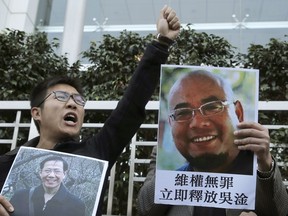 FILE - In this Dec. 27, 2017, file photo, pro-democracy activists hold pictures of Chinese activists Qin Yongmin, left, and Wu Gan outside the Chinese central government's liaison office in Hong Kong. China on Wednesday, July 11, 2018, has sentenced Qin, a veteran pro-democracy campaigner, to 13 years in prison on vaguely defined subversion charges, one day after releasing the widow of a Nobel Peace Prize laureate.