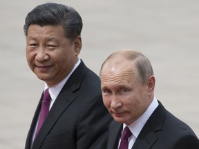 FILE - In this June 8, 2018, file photo, Russian President Vladimir Putin, right, and Chinese President Xi Jinping walk together during a welcome ceremony outside the Great Hall of the People in Beijing, China. If Donald Trump is serious about his public courtship of Vladimir Putin, he may want to take pointers from one of the Russian leader's longtime suitors: Chinese President Xi Jinping. In this political love triangle, Putin and Xi are tied by strategic need and a rare dose of personal affection, while Trump's effusive display in Helsinki showed him as an earnest admirer of the man leading a country long considered America's adversary.