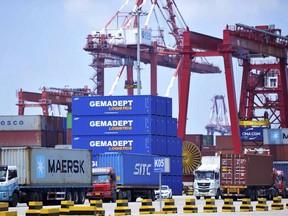 FILE - In this July 6, 2018, file photo, trucks haul containers from a container port in Qingdao in eastern China's Shandong province. China's trade grew by double digits in June despite mounting tensions with Washington but the government warned it will face "rising instabilities and uncertainties." (Chinatopix via AP, File)