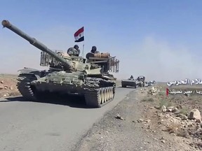 This frame grab from video provided on Saturday, July 7, 2018 by the government-controlled Syrian Central Military Media, shows a convoy of Syrian military vehicles near the Naseeb border crossing with Jordan, in the southern province of Daraa, Syria.