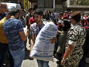 Members of the Lebanese general security organise Syrian refugees gathered to cross into Syria at the Lebanese border crossing point of Masnaa, in Bekaa Valley, Lebanon, Saturday, July 28, 2018. About a thousand Syrian refugees are expected to make the crossing on Saturday, after having requested permission from the Lebanese and Syrian governments.