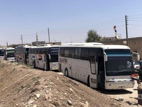 In this photo released by the Syrian official news agency SANA, buses arrive in Tel el-Eis, the crossing between Aleppo and Idlib provinces, Syria, Wednesday, July 18, 2018. About 7,000 Syrians were expected to be evacuated from the two pro-government villages of Foua and Kfarya, ending their three-year siege by insurgents who control the surrounding areas. (SANA via AP)