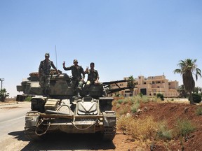 In this photo released by the Syrian official news agency SANA, shows Syrian soldiers flashing the victory sign as they sit on their military vehicle at Naseeb border crossing with Jordan, in the southern province of Daraa, Syria, Saturday, July 7, 2018. Syrian troops captured the Naseeb border crossing a day earlier following a crushing two-week offensive, and after rebels announced they had reached an agreement with Russian mediators to end the violence in the southern province of Daraa and surrender the crossing. (SANA via AP)