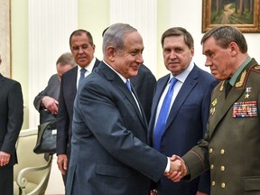 Israeli Prime Minister Benjamin Netanyahu, centre, shakes hands with Head of the General Staff of the Armed Forces of Russia and First Deputy Defense Minister Valery Gerasimov, right, as Russian President Vladimir Putin, left, looks on during their meeting at the Kremlin in Moscow, Wednesday, July 11, 2018.