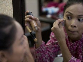 In this June 20, 2018 photo, Johandrys Colls practices makeup during a class at the Belankazar Modeling Academy in Caracas, Venezuela. In Venezuela, competing comes at a high price: elaborate sequined gowns and pricey cosmetic surgeries are out of reach for most in a country where inflation is running in the five digits and state workers earn about $3 a month.