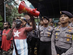 FILE - In this March 20, 2017, file photo, a Papuan activist whose body is painted in the colors of "Morning Star" separatist flag shouts slogans as police officers stand guard during a protest in Jakarta, Indonesia. Amnesty International said Monday, July 2, 2018 there have been dozens of unlawful killings by security forces in Indonesia's easternmost Papua region since 2008, including targeted slayings of activists, and a near total absence of justice for the mainly indigenous victims.