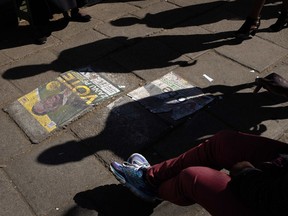 Zimbabweans walk past a poster of President Emmerson Mnangagwa glued on the ground in in Bulawayo, Zimbabwe, Wednesday July 25, 2018. Nelson Chamisa, head of the MDC opposition party, urged supporters to vote "overwhelmingly for change," in the Presidential elections scheduled to take place Monday July 30, 2018.