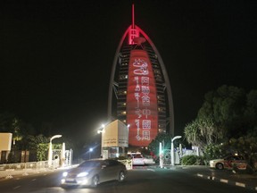 In this Wednesday, July 18, 2018 photo, a sign reading  "UAE Chinese Week" in Chinese and Arabic is projected  onto the Bus Al Arab luxury hotel to celebrate the UAE Chinese Week in Dubai, United Arab Emirates. Chinese President Xi Jinping is heading to Abu Dhabi in his first trip to the United Arab Emirates as the leader of China as the two countries look to strengthen trade ties and expand investment.