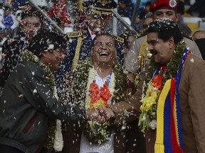 FILE - In this June 14, 2014 file photo, Bolivia's President Evo Morales, left, and Venezuela's President Nicolas Maduro, right, shake hands as Ecuador's President Rafael Correa, center, laughs during the welcoming ceremony for delegates of the G77 + China Summit in Santa Cruz, Bolivia. The Ecuadorean government has sent on Wednesday, July 4, 2018, a protest note to the governments of Venezuela and Bolivia regarding their comments on the arrest warrant issued against Ex-President Correa, (AP Photo, File)