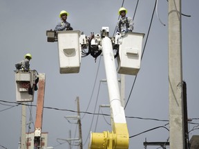 FILE - In this Oct. 19, 2017 file photo, a brigade from the Electric Power Authority repairs distribution lines damaged by Hurricane Maria in the Cantera community of San Juan, Puerto Rico. Jose Ortiz will take over Puerto Rico's Electric Power Authority on July 23, 2018, the company's second CEO in two weeks as it struggles with leadership issues, bankruptcy and the restoration of electricity to hundreds who have remained in the dark since Hurricane Maria.